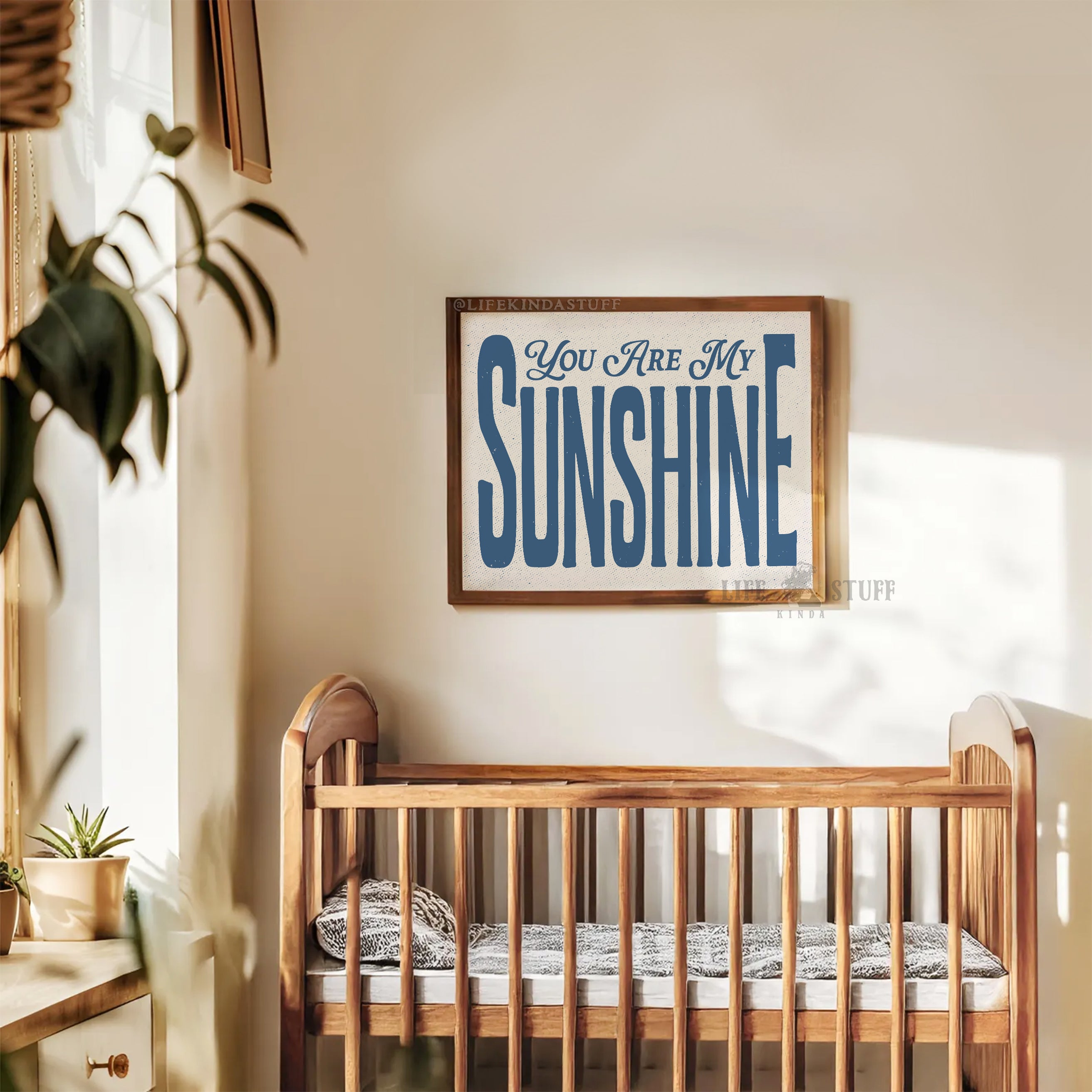 Nursery room with wooden crib and 'You Are My Sunshine' sign in retro typography on the wall.